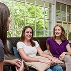 three young women talking on couch