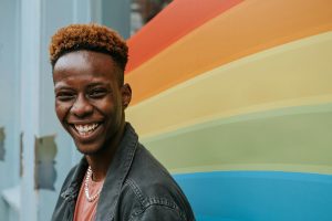 smiling man in front of Pride colors