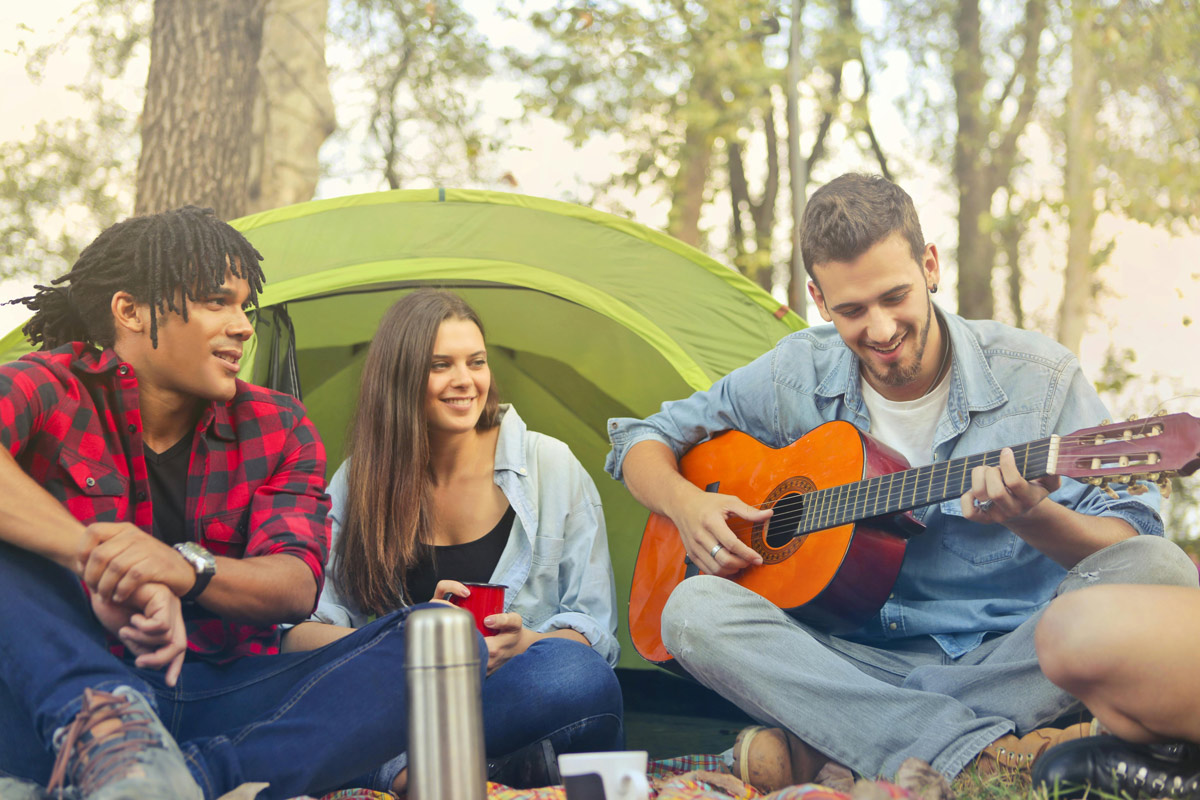Young man playing guitar and relaxing with friends