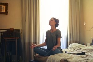 Mindful woman meditating on bed