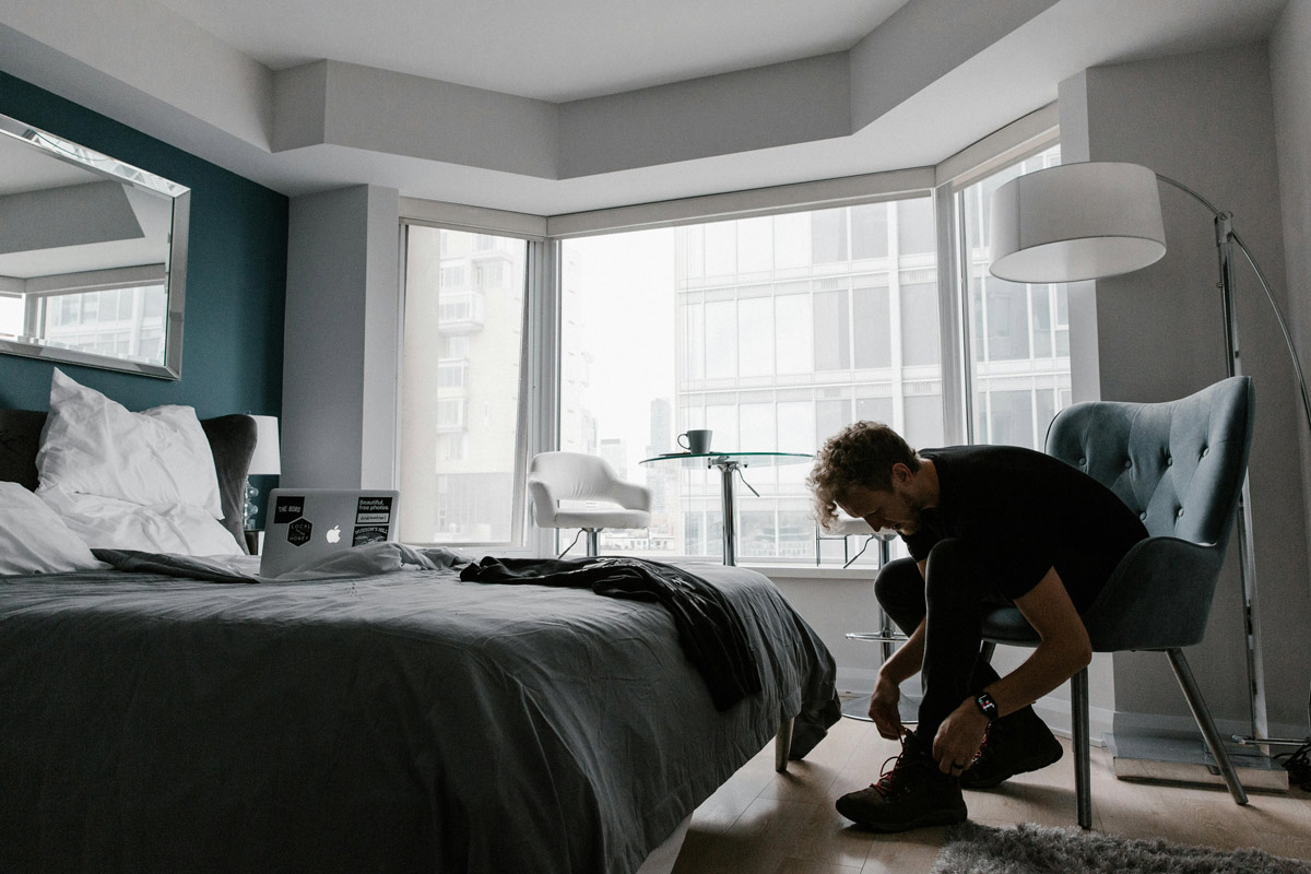 Man tying shoes in bedroom