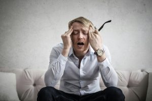 Upset man on couch with head in hands.