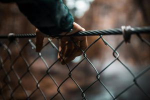 Hand on chain link fence.