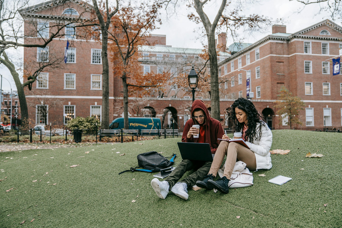 Two college students studying on campus lawn