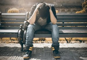 Troubled man on bench with head in hands