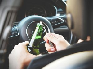 Close up of driver opening beer bottle in a car