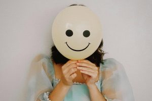 Person in party dress with smiley face balloon