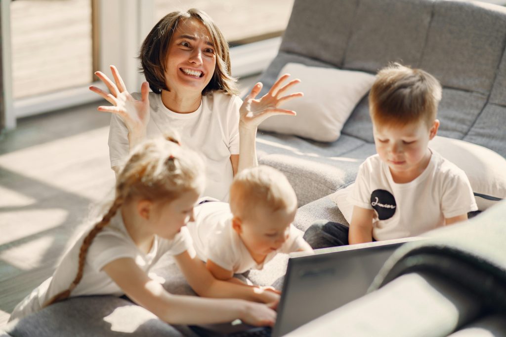 Exasperated mother with young children using a laptop computer.