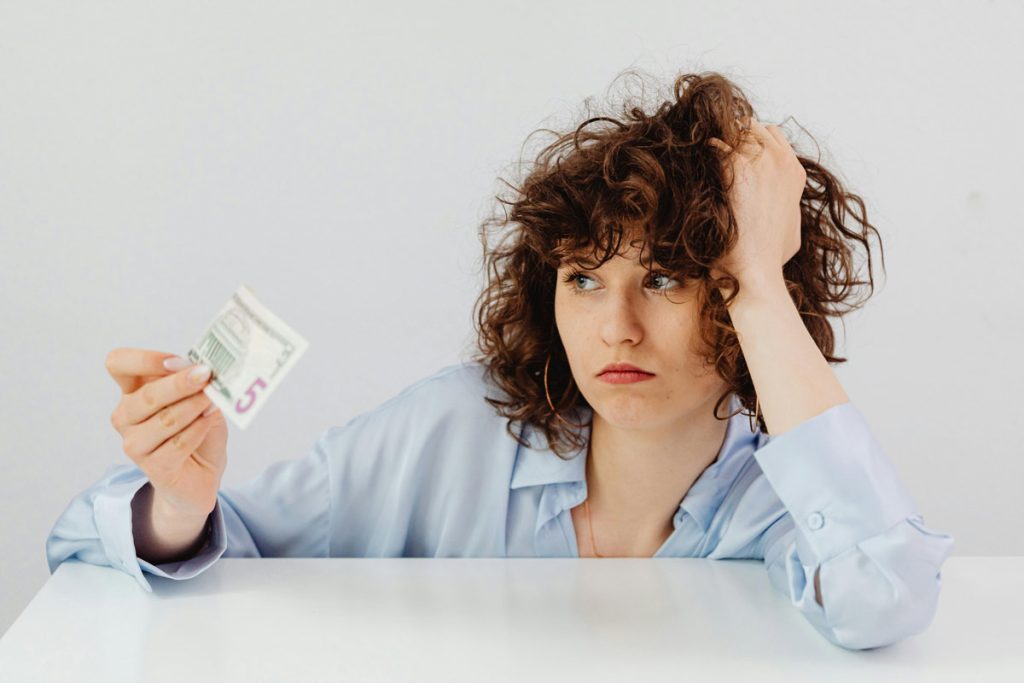 Worried woman holding a five dollar bill