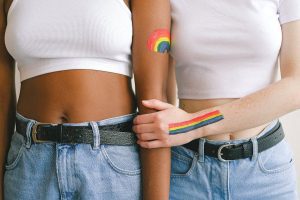 Two people side by side with rainbow colors on their arms illustrating LGBTQ+ identity and mental health