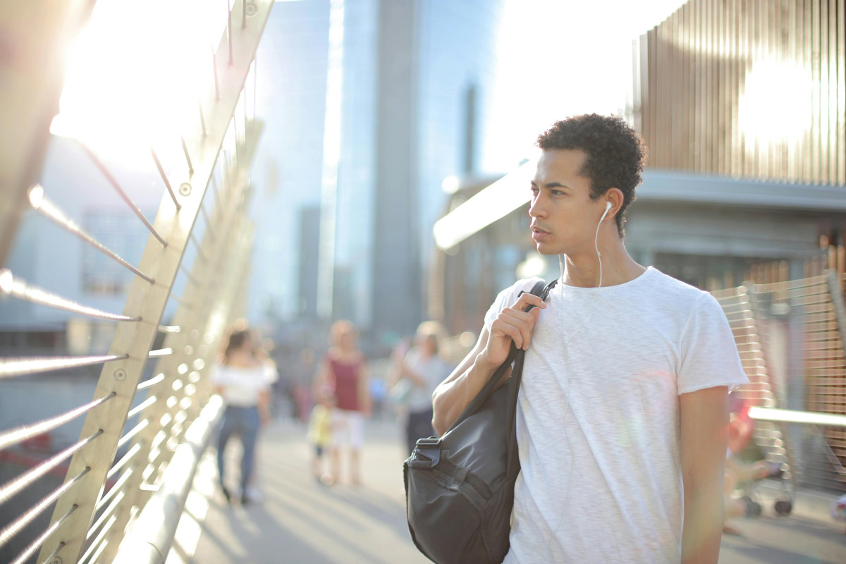 Young man walking outside with backpack.