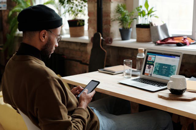 A man sitting in front of a desk, looking at his phone.