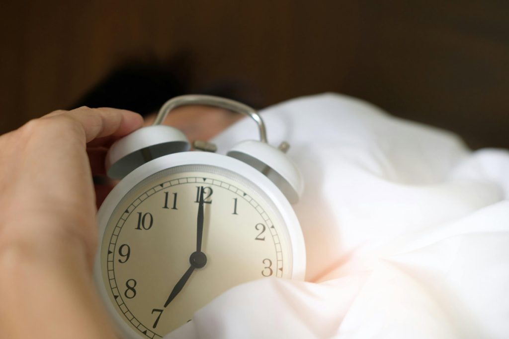 Hand reaching for alarm clock.