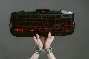 Chained hands holding up a keyboard.