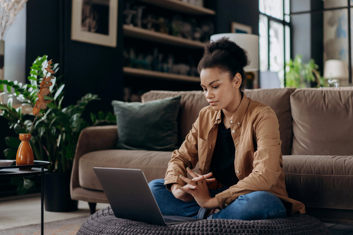 Young woman sitting on floor in front of laptop.