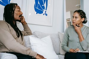 Black therapist and client talking on couch.